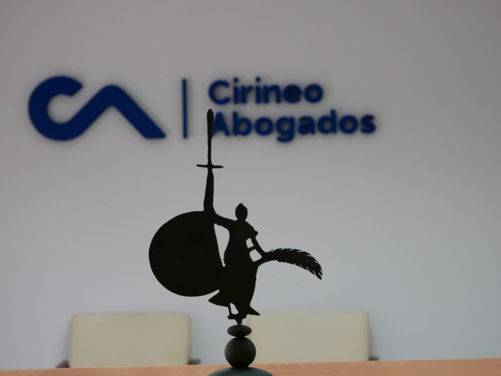 Silueta de una figura sobre un escritorio con el logo de Cirineo Abogados al fondo.